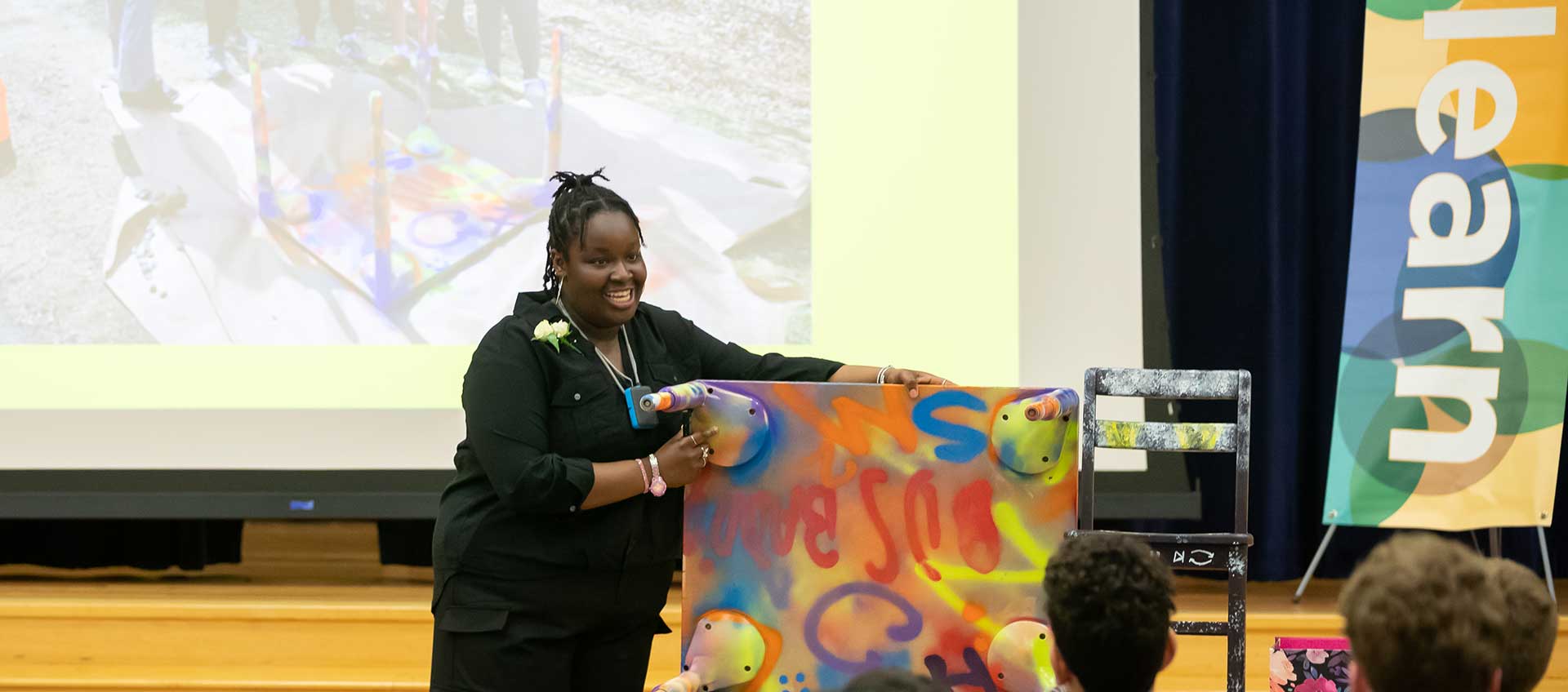 A girl presents a colorful painting during her Capstone presentation