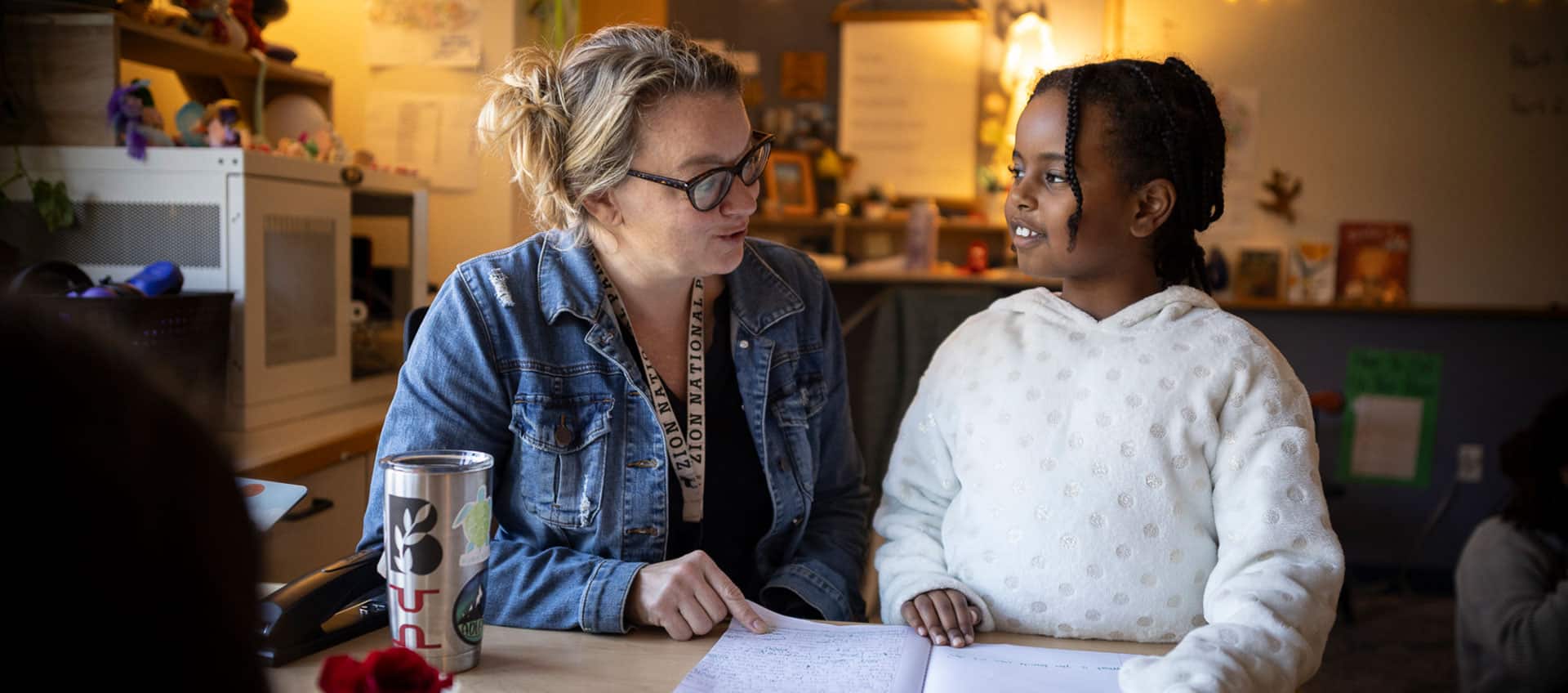 Teacher Larissa Rochford talks with a student at her desk