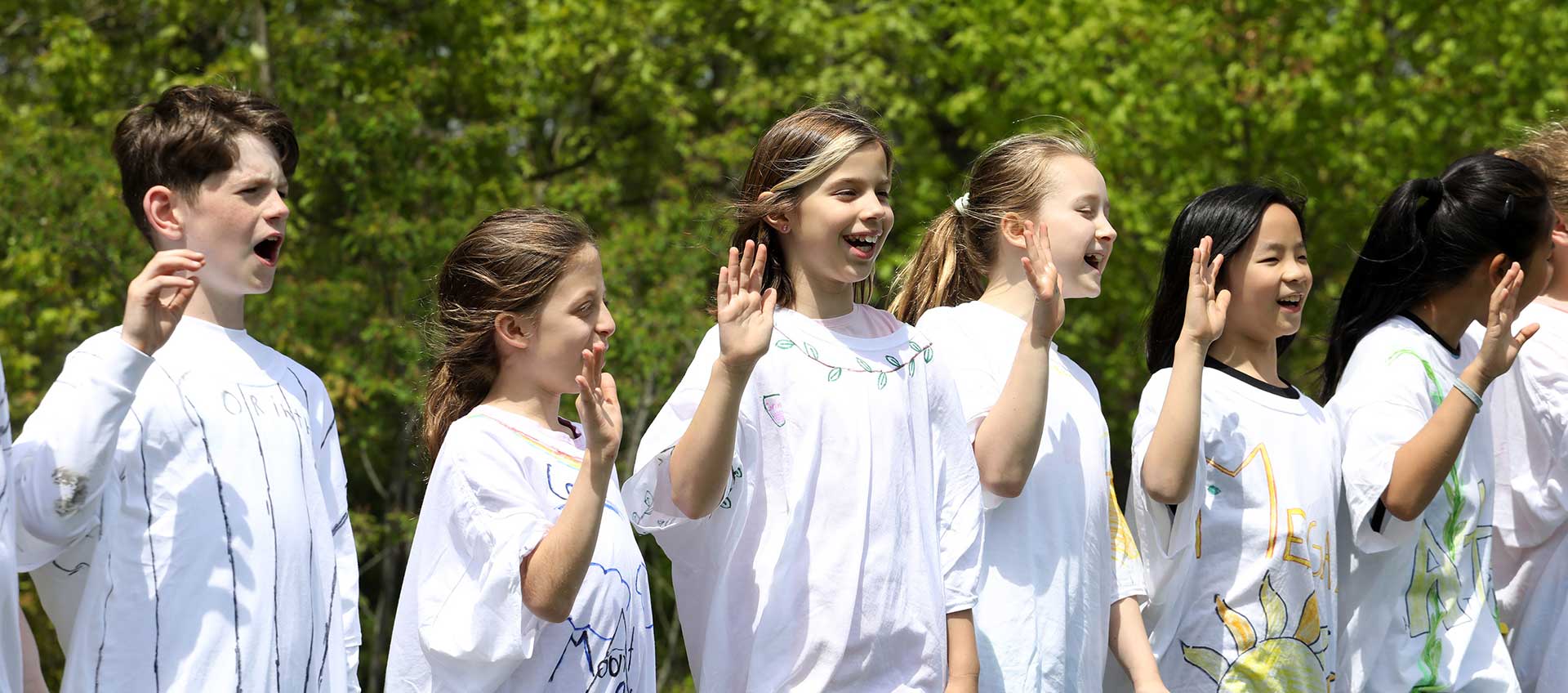 Five students stand with hands raised at the start of their Greek Olympics