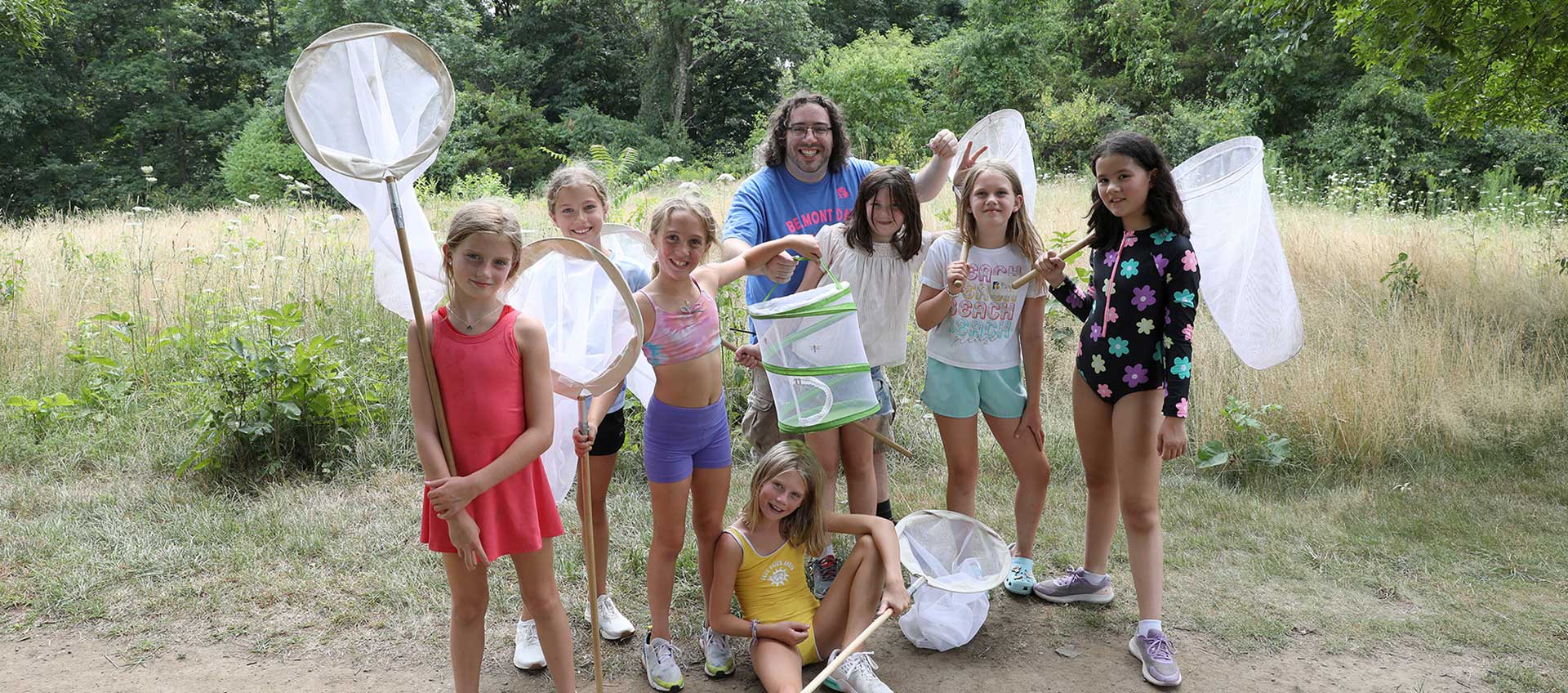 A group of campers in the woods collecting and observing insectrs