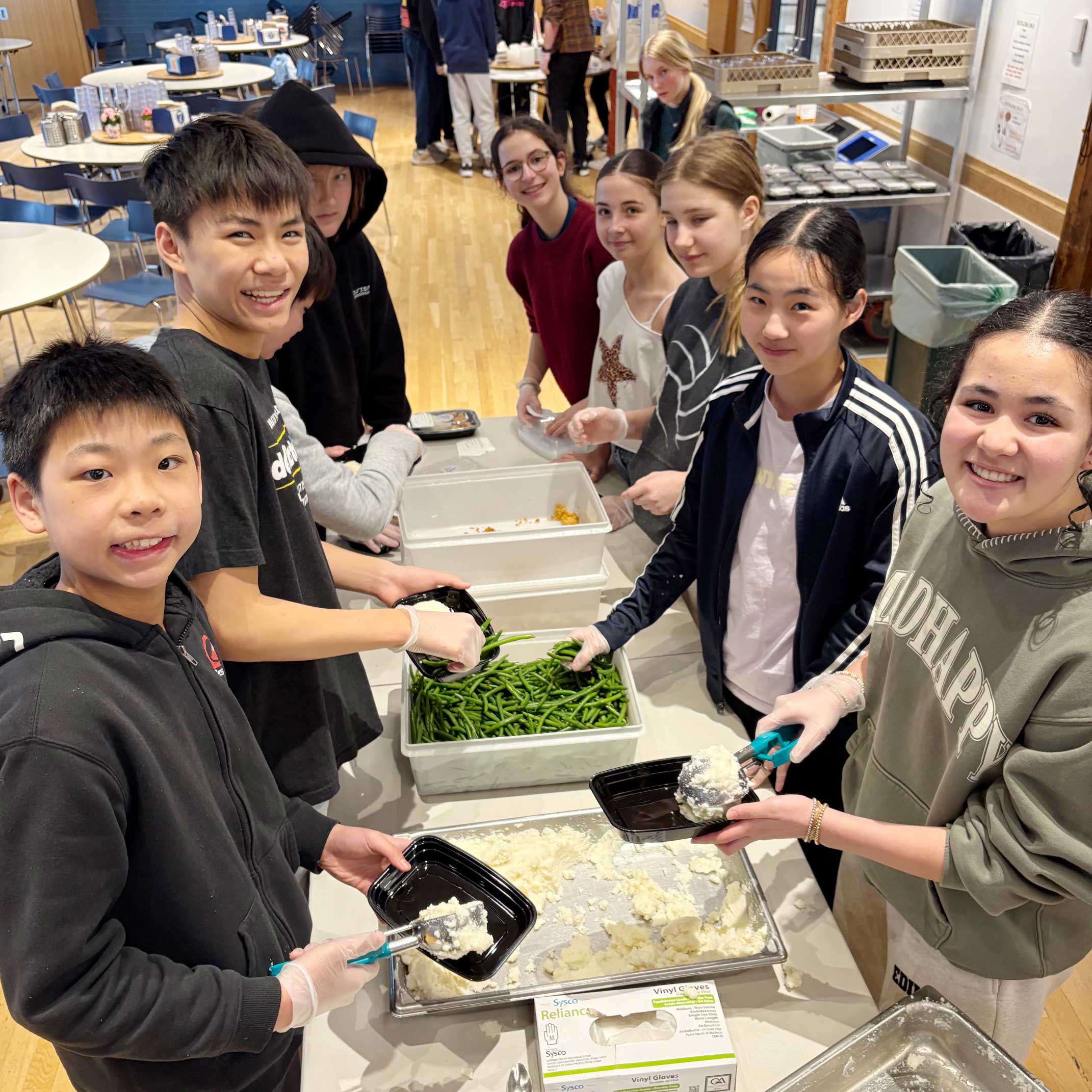 Several students around a table packaging food